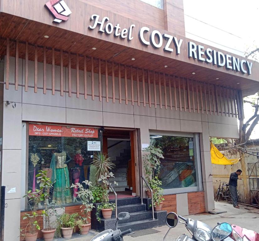 uma loja em frente a um restaurante acolhedor do hotel com uma moto estacionada fora em Hotel Cozy Residency em Jabalpur