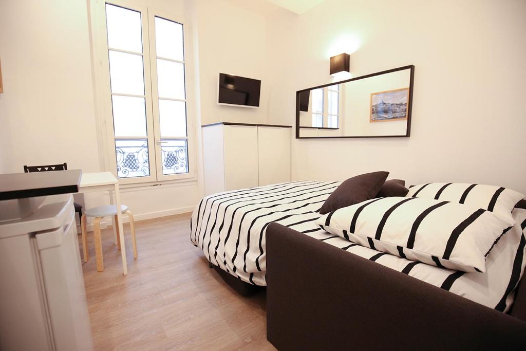 ein Schlafzimmer mit einem Bett, einem Schreibtisch und einem Spiegel in der Unterkunft Studio Saint Ferreol hyper centre 3-1 in Marseille