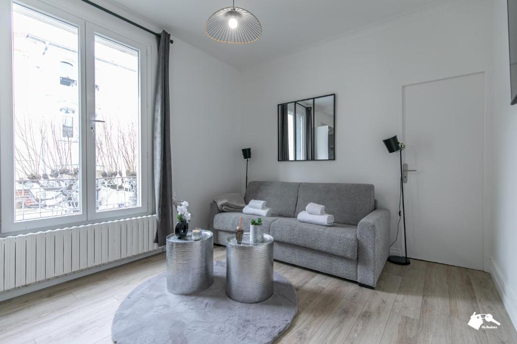 a living room with a gray couch and a large window at MBA - Splendide Appart - Bobillot - Proche Vincennes in Montreuil