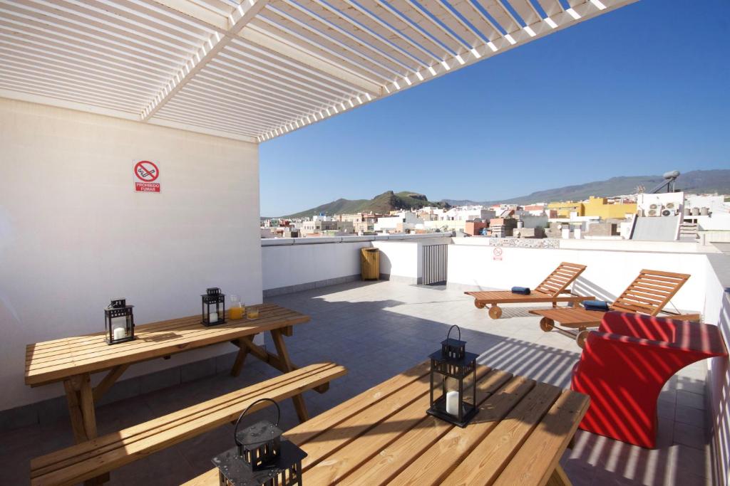 a patio with wooden tables and chairs on a roof at Two bedrooms apartment close to airport in Carrizal