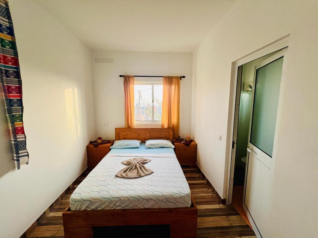 Habitación pequeña con 2 camas y ventana en Residencial Ribeira Torta, en Porto Novo