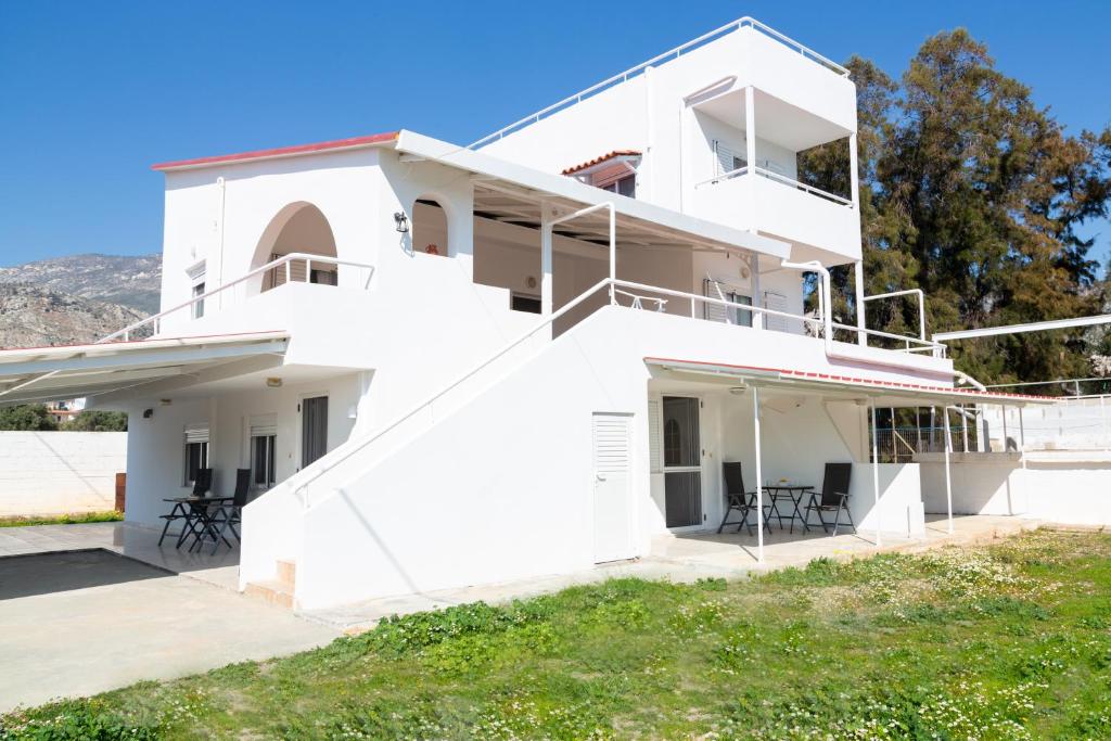 ein weißes Haus mit Stühlen davor in der Unterkunft Kineta Seaside Summer Apartments in Kineta