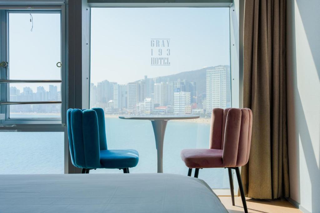 Duas cadeiras e uma mesa num quarto com uma janela em Gray 193 Hotel em Busan