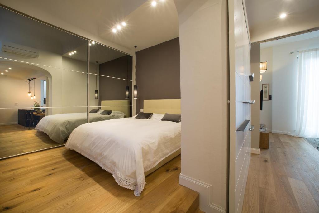 TA - One bedroom luxury apartment in the fashion district في فلورنسا: غرفة نوم بسريرين ومرآة كبيرة