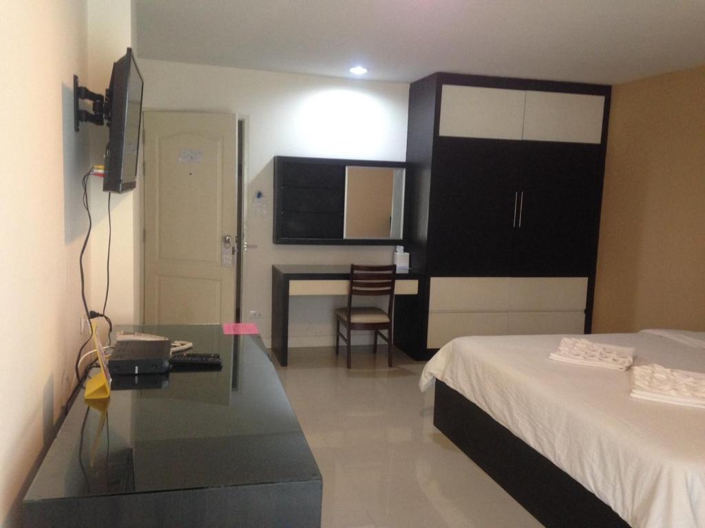Schlafzimmer mit einem Bett, einem Schreibtisch und einem Tisch in der Unterkunft Similan Mansion in Bangsaen