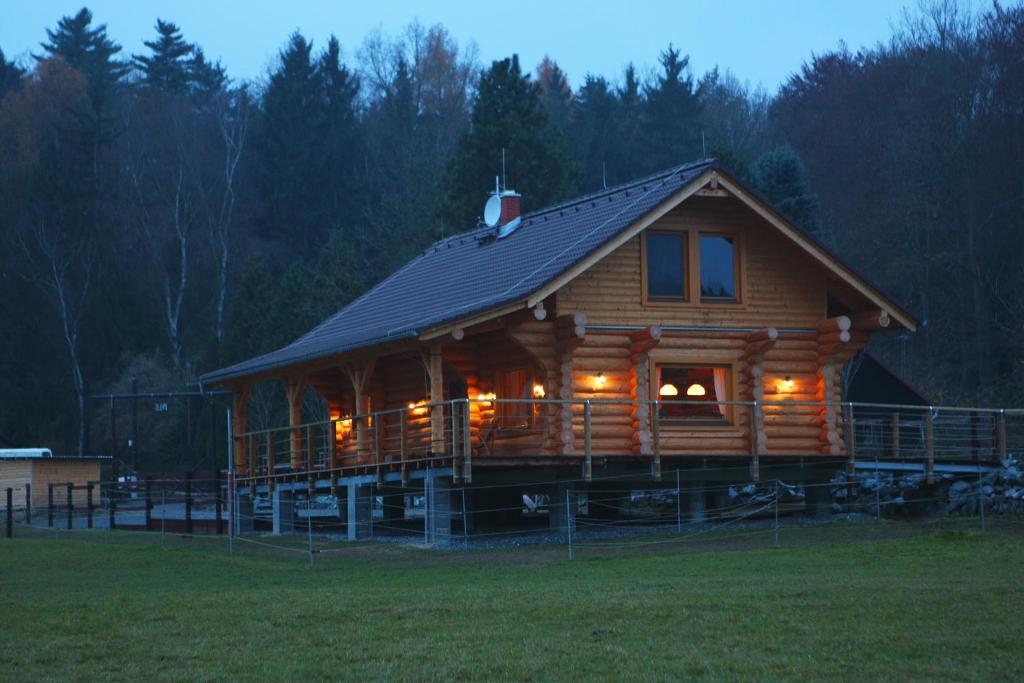 a large wooden cabin with lights in a field at Holiday Home MB Ranch in Bílá Hora