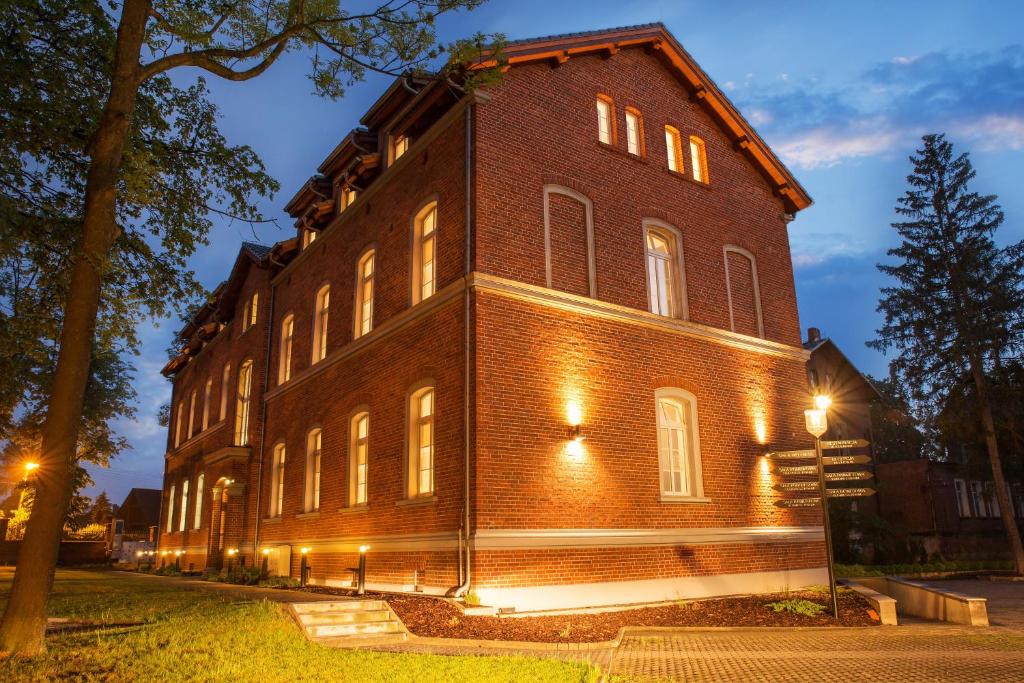 un bâtiment en briques avec des lumières sur son côté dans l'établissement Hotel Hugo Business & Spa, à Kędzierzyn-Koźle