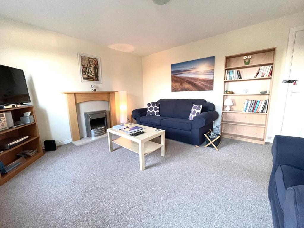 Sala de estar con sofá azul y mesa de centro en GuestReady-Close To Leeds City, Spacious, Sleeps 6 en Leeds