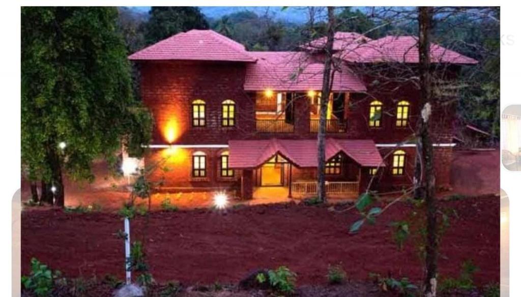 una gran casa de ladrillo con sus luces encendidas en Konkan Nest Resort, en Ganpatipule
