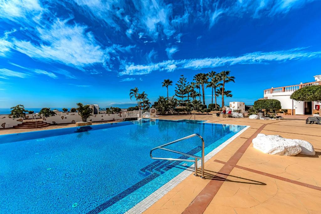 a swimming pool at a resort with a blue sky at Villa Las Mimosas in Adeje