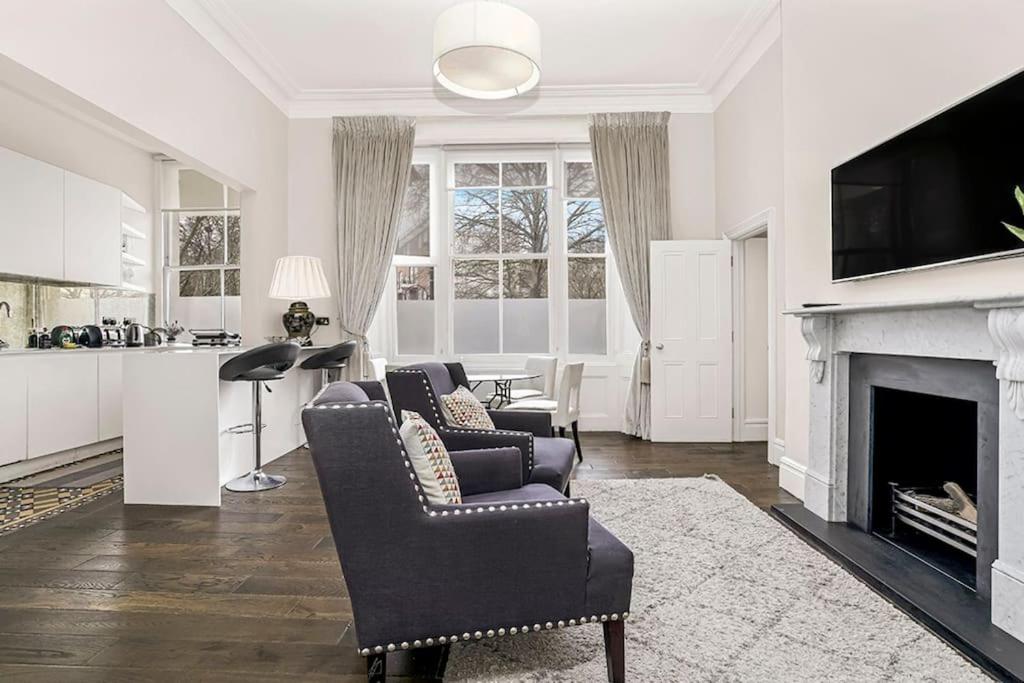 a living room with two chairs and a fireplace at Stunning 3 Bed Apartment- Paddington in London