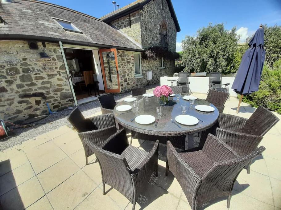 a patio with a table and chairs and an umbrella at Stunning Coastal Barn Conversion in Kingsbridge