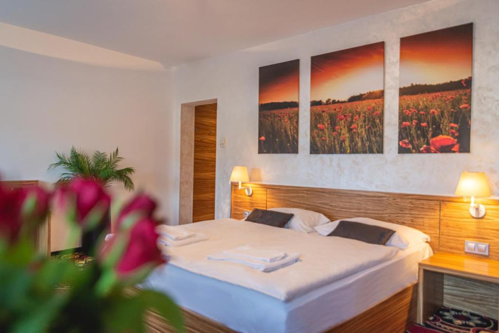 a bedroom with a bed with three paintings on the wall at Casino & Hotel ADMIRAL Kozina in Kozina