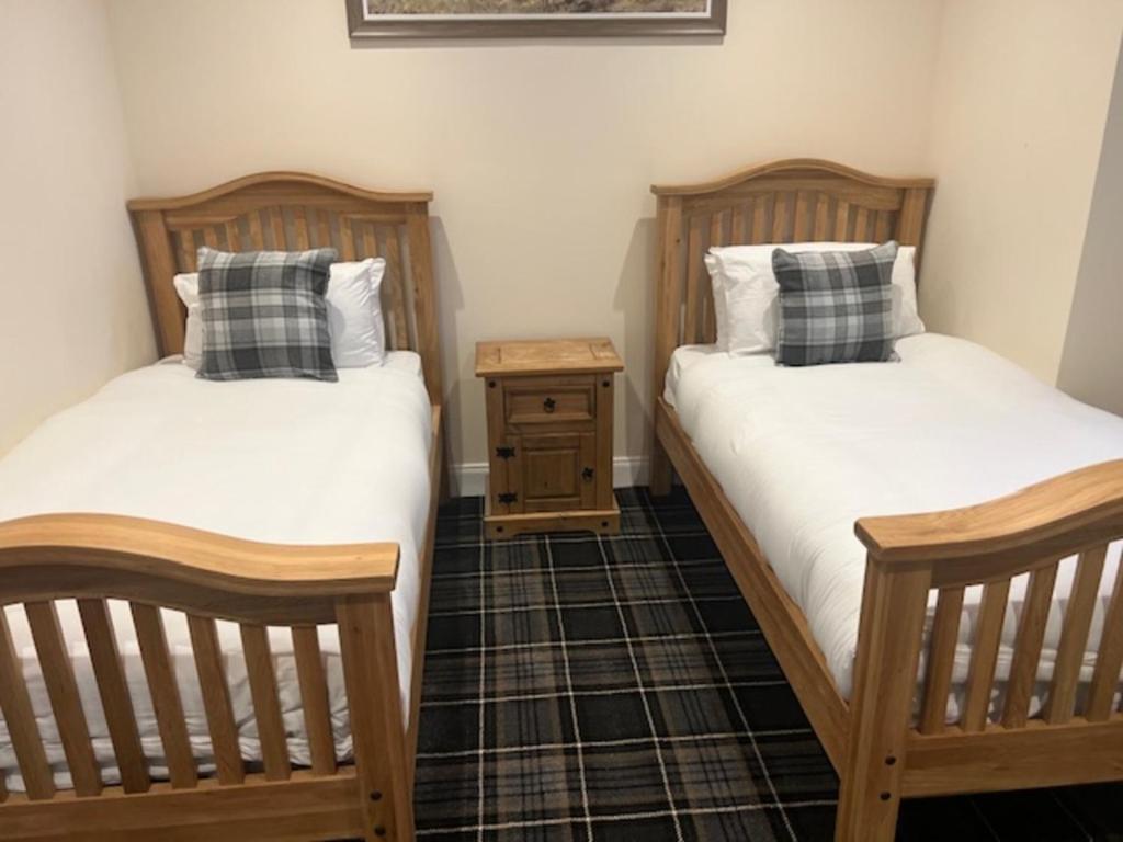 dos camas sentadas una al lado de la otra en una habitación en Waverley Inn Lodge, en Dingwall