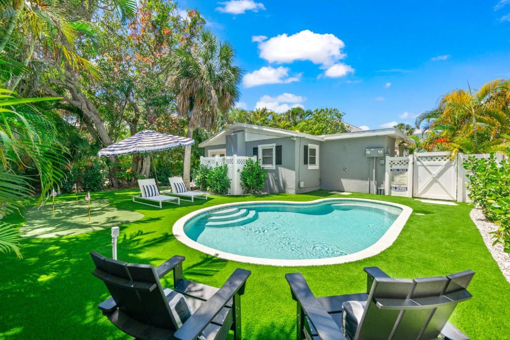 a yard with a pool and chairs and a house at The Cottage on Pine - Luxury Boho Beach Cottage wPvt Heated Pool On Pine Ave in Anna Maria