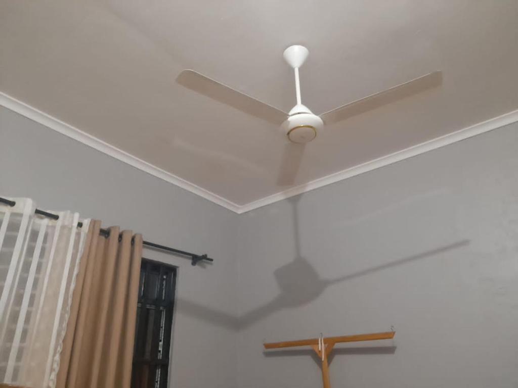 a white ceiling fan in a room with a window at KINYANJUI HOMES OO2 in Morogoro