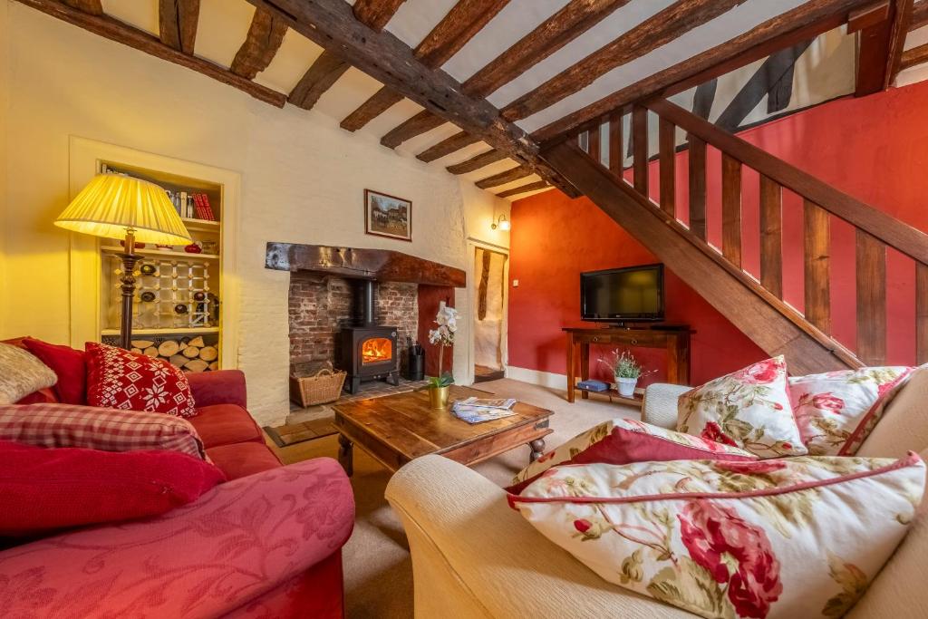 a living room with two couches and a fireplace at Medieval cottage in rural village - Duke's Lodge in Bildeston