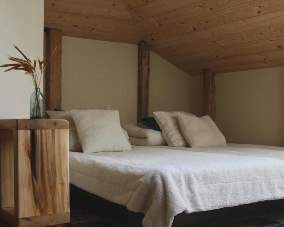 Bett mit weißer Bettwäsche und Kissen in einem Zimmer in der Unterkunft Inovatorių slėnis/ Innovators' valley in Antalieptė