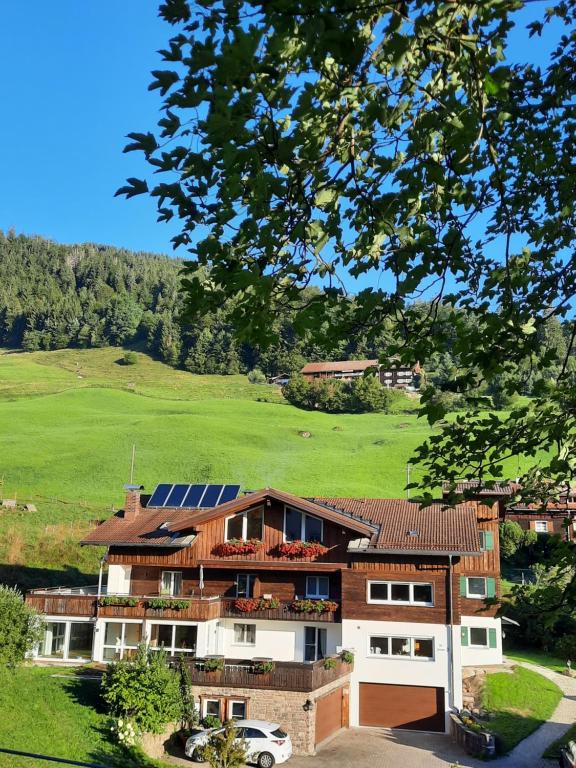 una casa con tetto solare e campo verde di Ferienwohnungen Im Ried a Blaichach