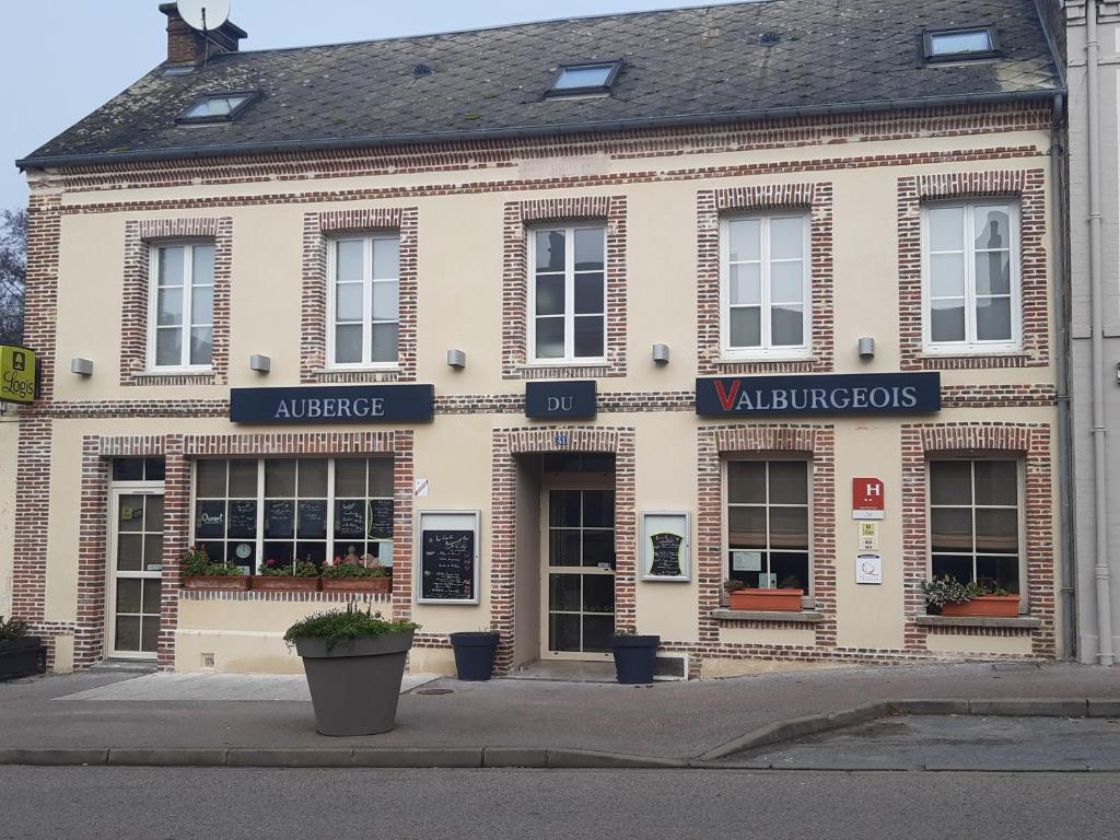 duży budynek z cegły z znakami na przedniej stronie w obiekcie Logis Auberge du Valburgeois w mieście Sainte-Gauburge-Sainte-Colombe