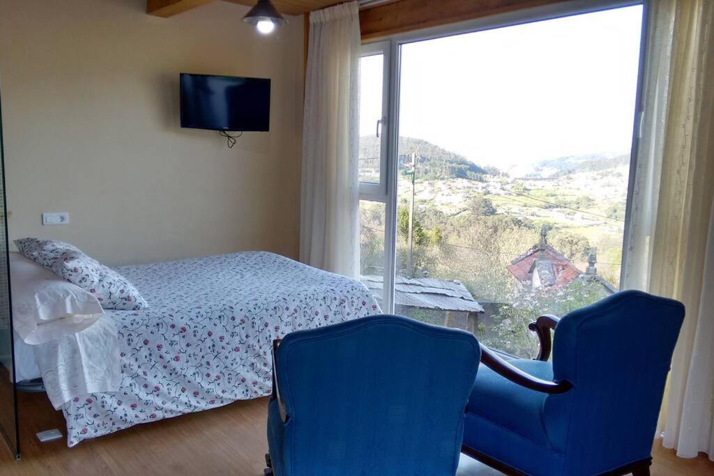 1 Schlafzimmer mit einem Bett, 2 Stühlen und einem Fenster in der Unterkunft Apartamento Portocelo, en Marín (Pontevedra) in Marín