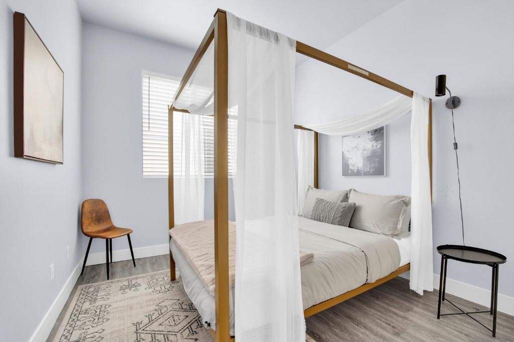 een witte slaapkamer met een hemelbed en een stoel bij NoHo by AvantStay North Hollywood Townhome in Los Angeles