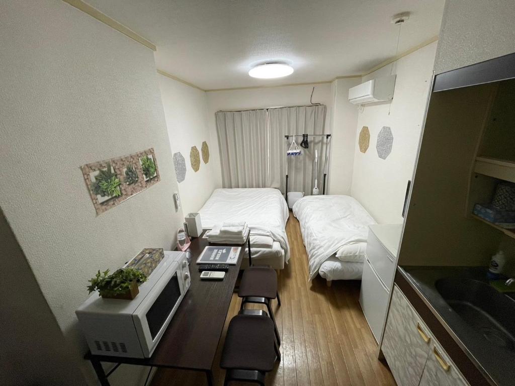 大阪市にあるMulti Stay Osaka Nipponbashi 32のベッド、デスク、テレビが備わる小さな客室です。