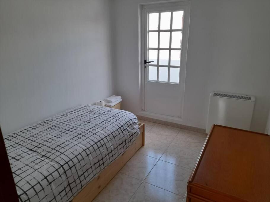 Schlafzimmer mit einem Bett, einem Fenster und einer Tür in der Unterkunft Ático completamente equipado Plaza de España in Ferrol