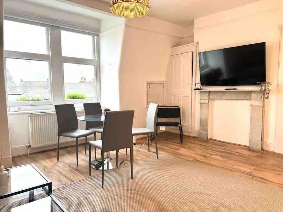 a living room with a table and chairs and a flat screen tv at One Bed Apartment- Muswell Hill in London