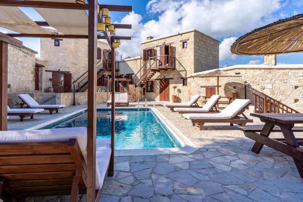 a pool with chaise lounge chairs and a house at Stone Court Boutique Studios in Paphos