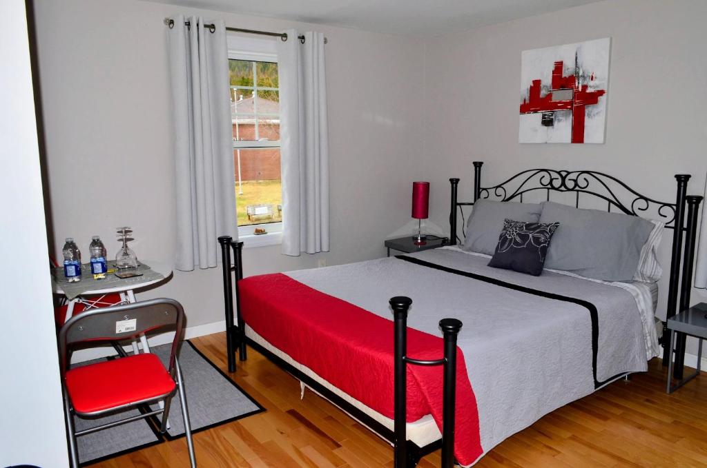 a bedroom with a bed and a table and a chair at Gîte Nycole in Perce