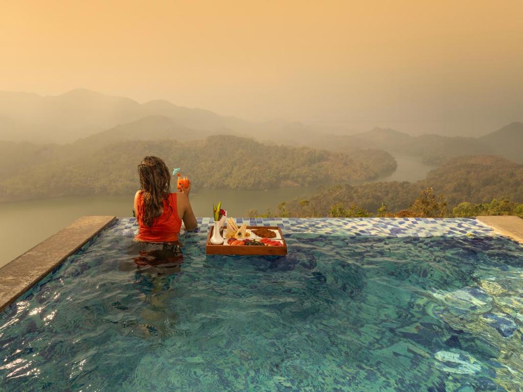 a woman sitting in a swimming pool with a dog in a boat at Ragamaya Resort & Spa Munnar in Munnar