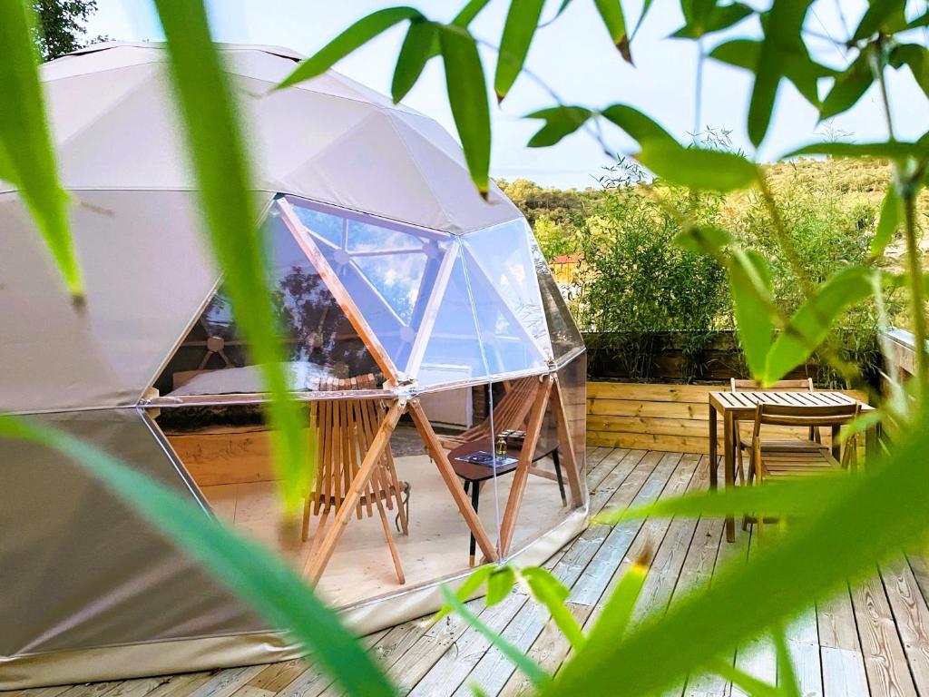 a dome tent with a table and chairs on a deck at Dôme Sirius - Provence étoilée in Rocbaron