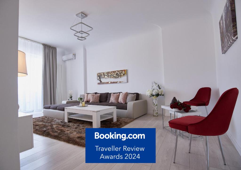 a white living room with a couch and red chairs at Metropole Apartments Old Town in Bucharest