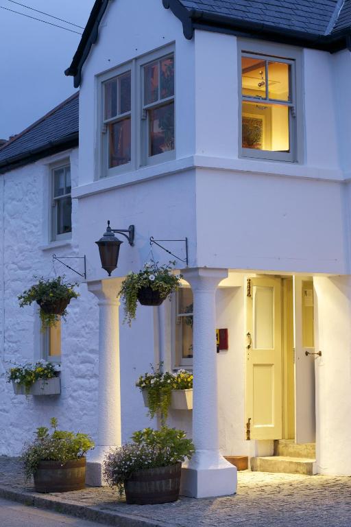 a white house with potted plants and a yellow door at The Plume of Feathers in Mitchell