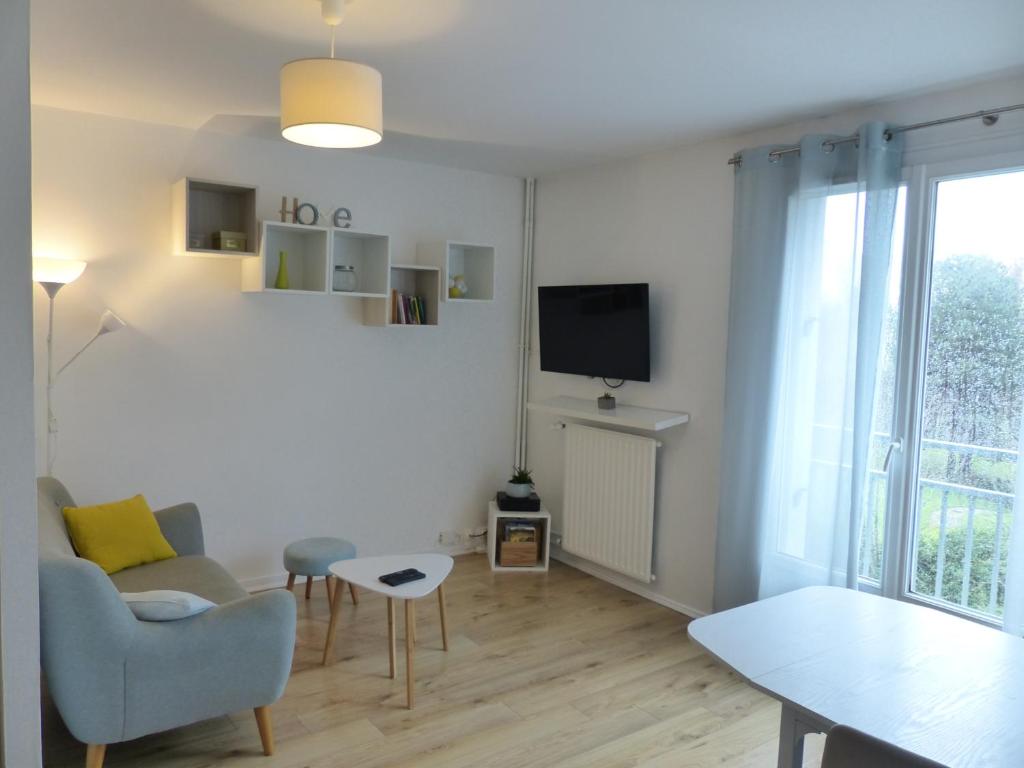 un salon avec une télévision, un canapé et une table dans l'établissement RARE : Calme et détente à Nantes !, à Nantes