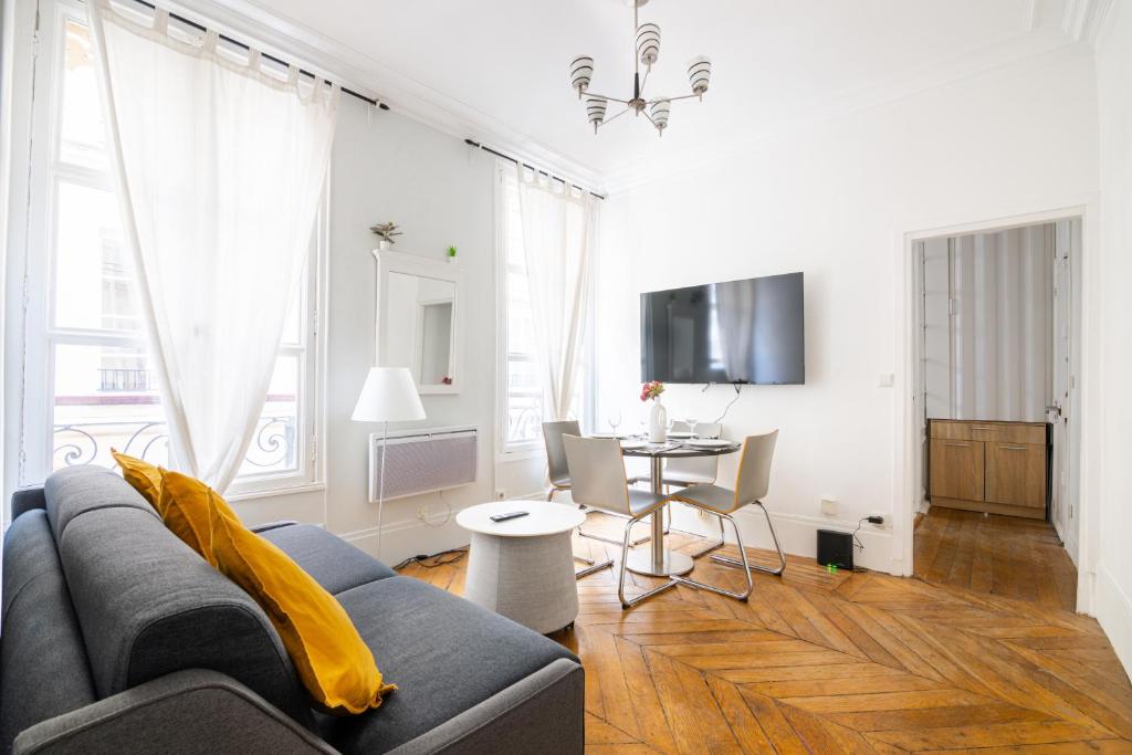 a living room with a couch and a table at Appartement Quartier Musée du Louvre Free Netflix in Paris