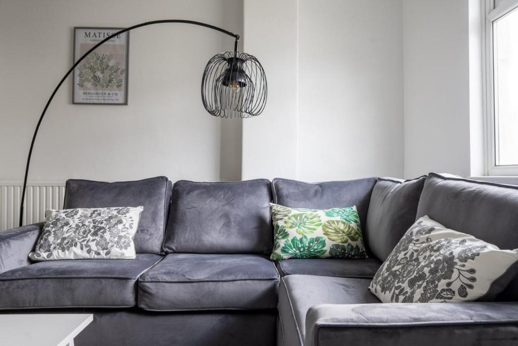 a blue couch with pillows in a living room at Spacious 4-Bedroom Apt | Pool Table in Cardiff