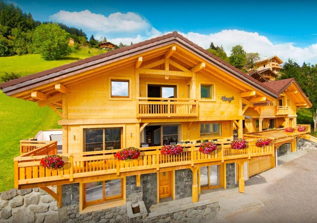 ein großes Holzhaus mit Balkon in der Unterkunft Chalet Nougat - Les Congères in Manigod