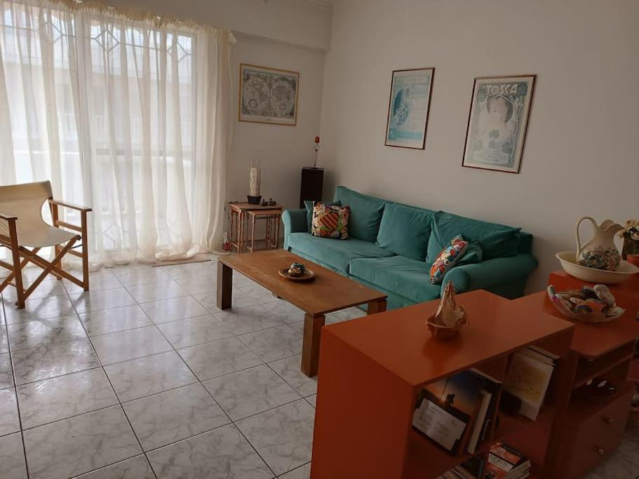 een woonkamer met een groene bank en een tafel bij Poppy's Akrata Beach Apartment in Paralía Akrátas