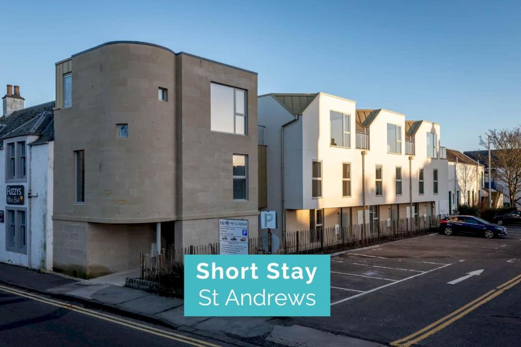 a building on a street with a sign that reads short stay st anomalies at Argyle Rigg * Deluxe Central Townhouse * Balcony in St. Andrews