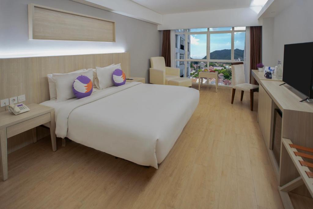 a bedroom with a large white bed and a television at FOX Hotel Gorontalo in Gorontalo
