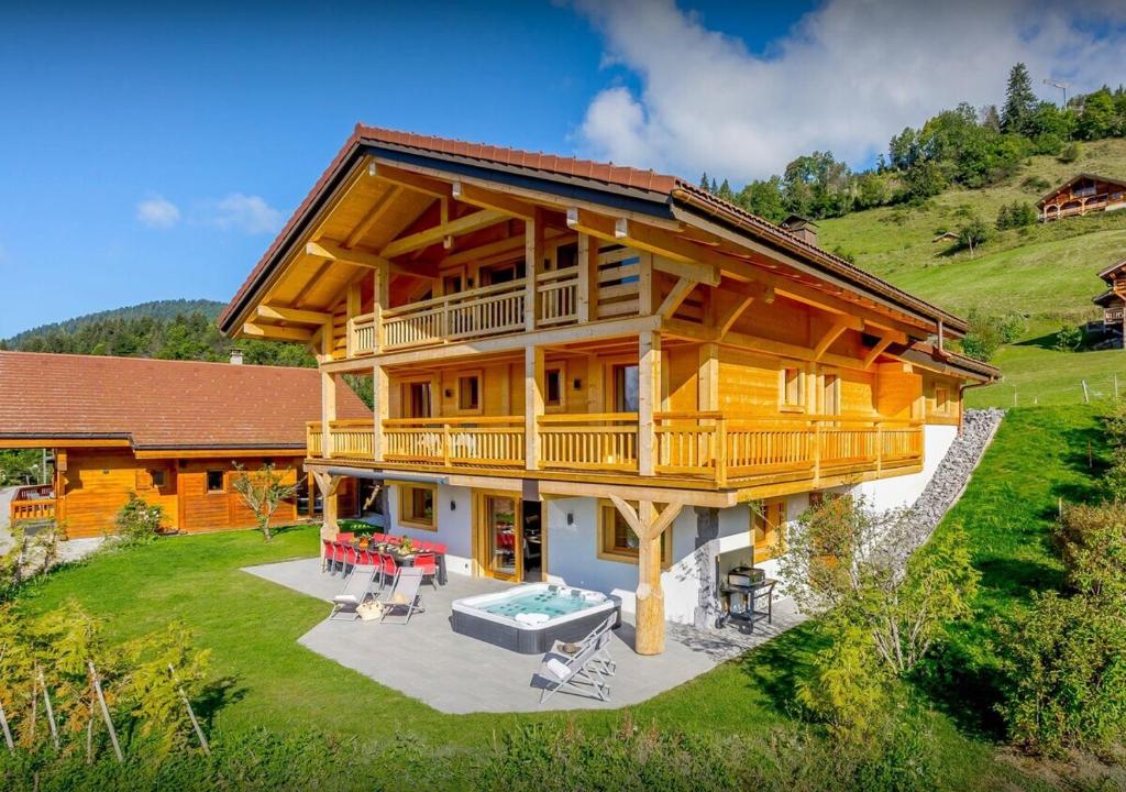 a large wooden house with a deck and patio at Chalet Chamallow - Les Congères in Manigod
