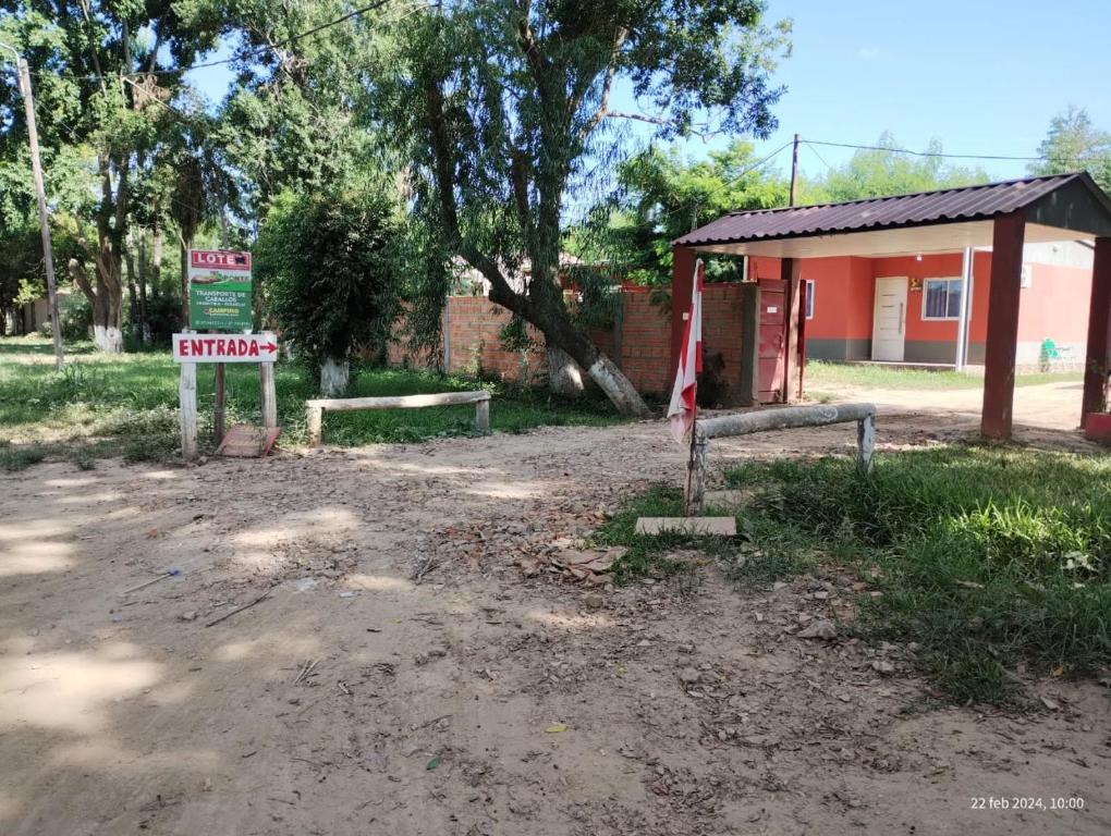 a building with a sign in front of a dirt road at Camping Caperucita Roja in Clorinda