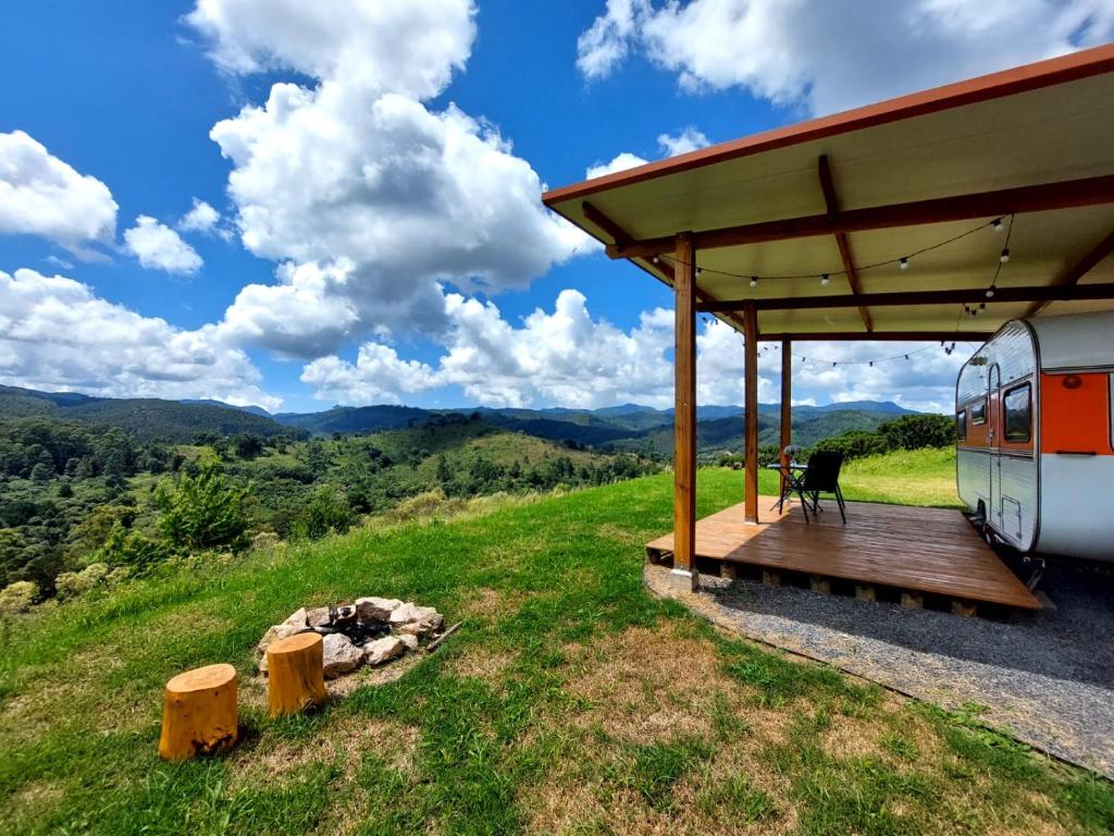 uma cabina com uma mesa e uma cadeira sob um telhado em Trailer na montanha próximo de Monte Verde em Camanducaia