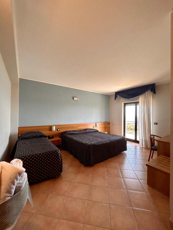 two beds in a room with a room with a window at Hotel Lachea in Acitrezza