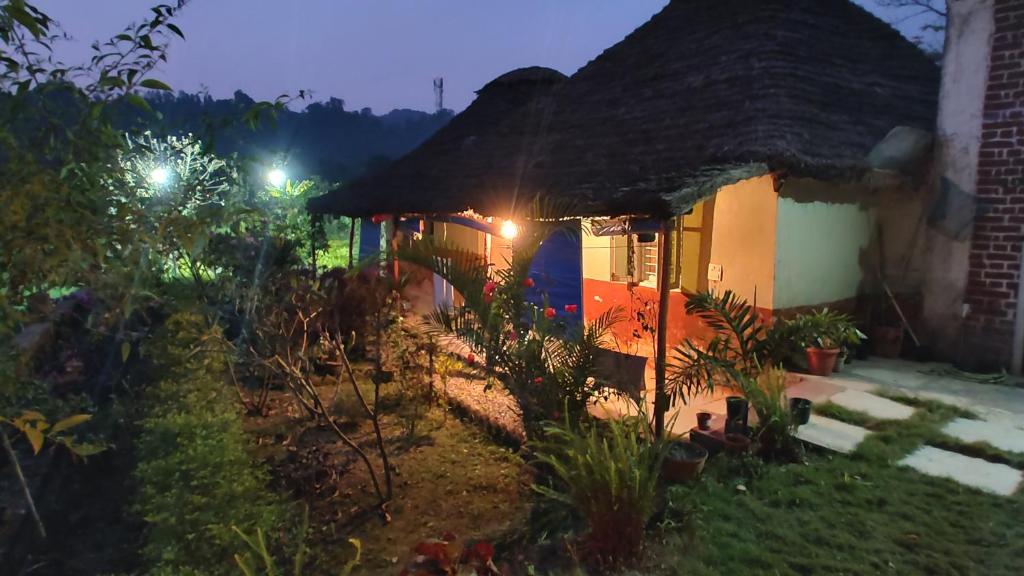 a small house with a thatched roof at night at Shivoham the earthen Home in Dehradun