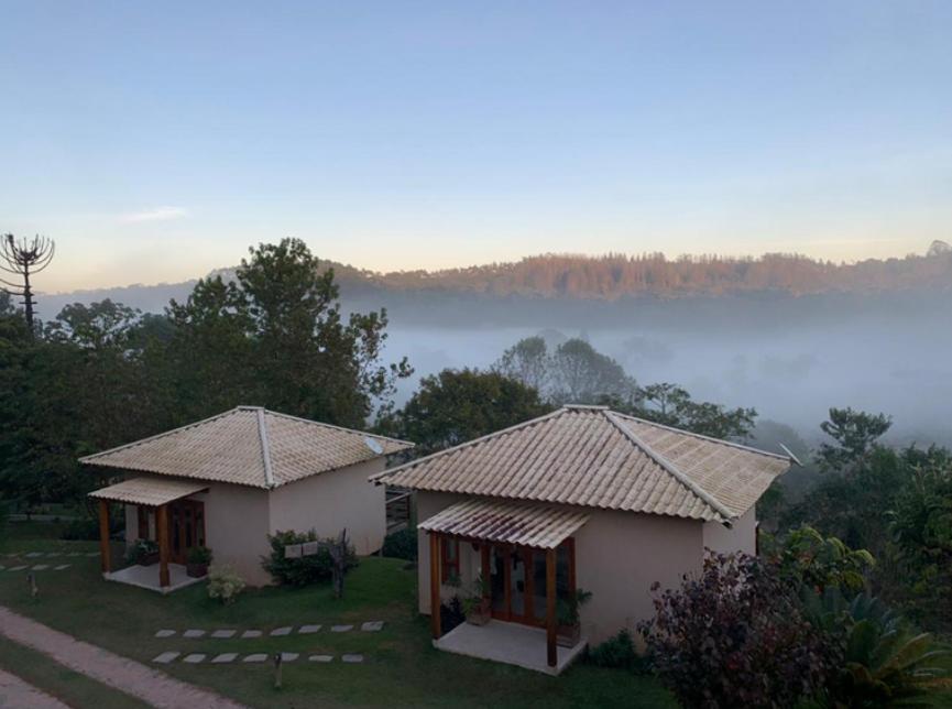 2 casas pequeñas con vistas a un valle nublado en Villa Uliana - Bangalôs VILLA en Domingos Martins