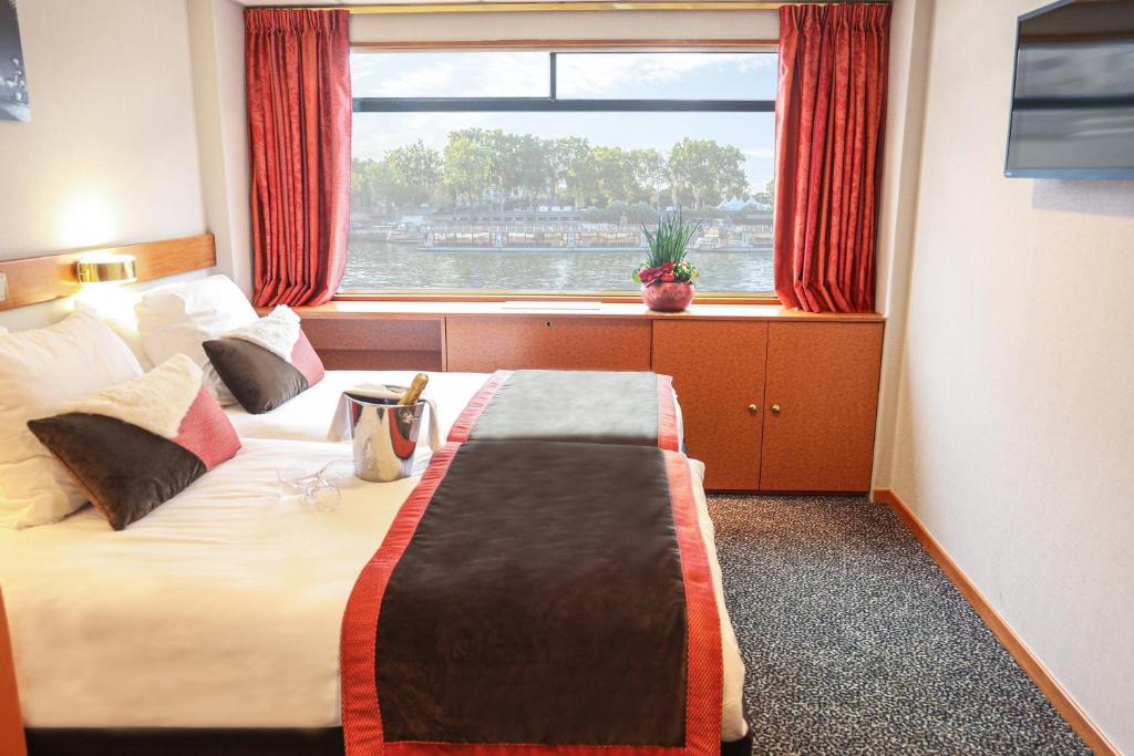 a hotel room with a large bed with a window at Bateau Seine Princess by CroisiEurope in Paris