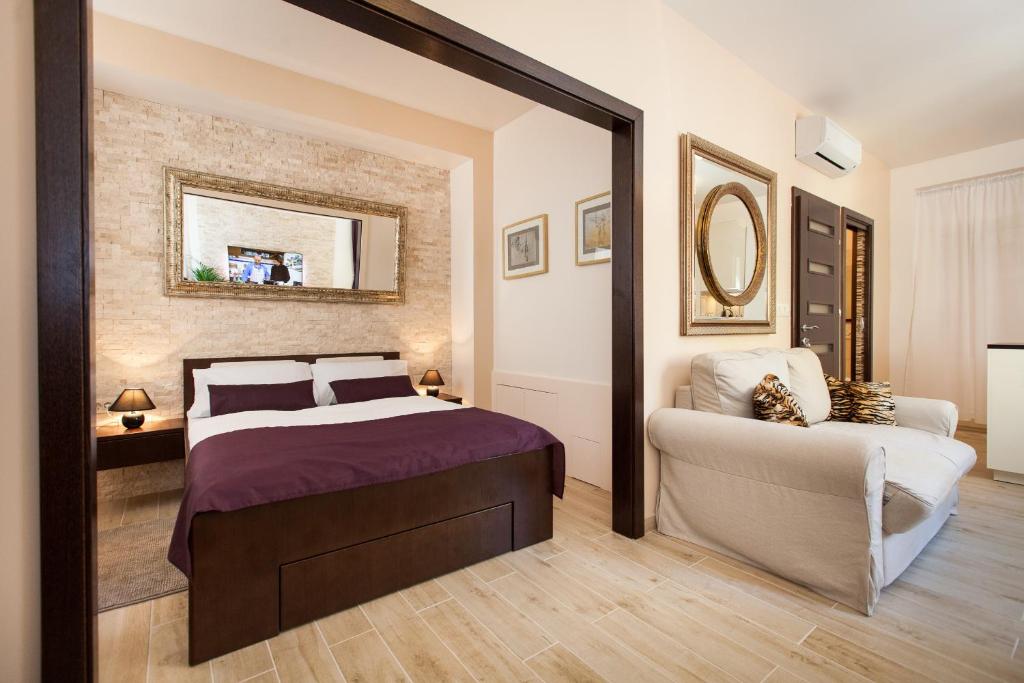 a bedroom with a bed and a couch and a mirror at Apartments Villa Bianca in Rovinj